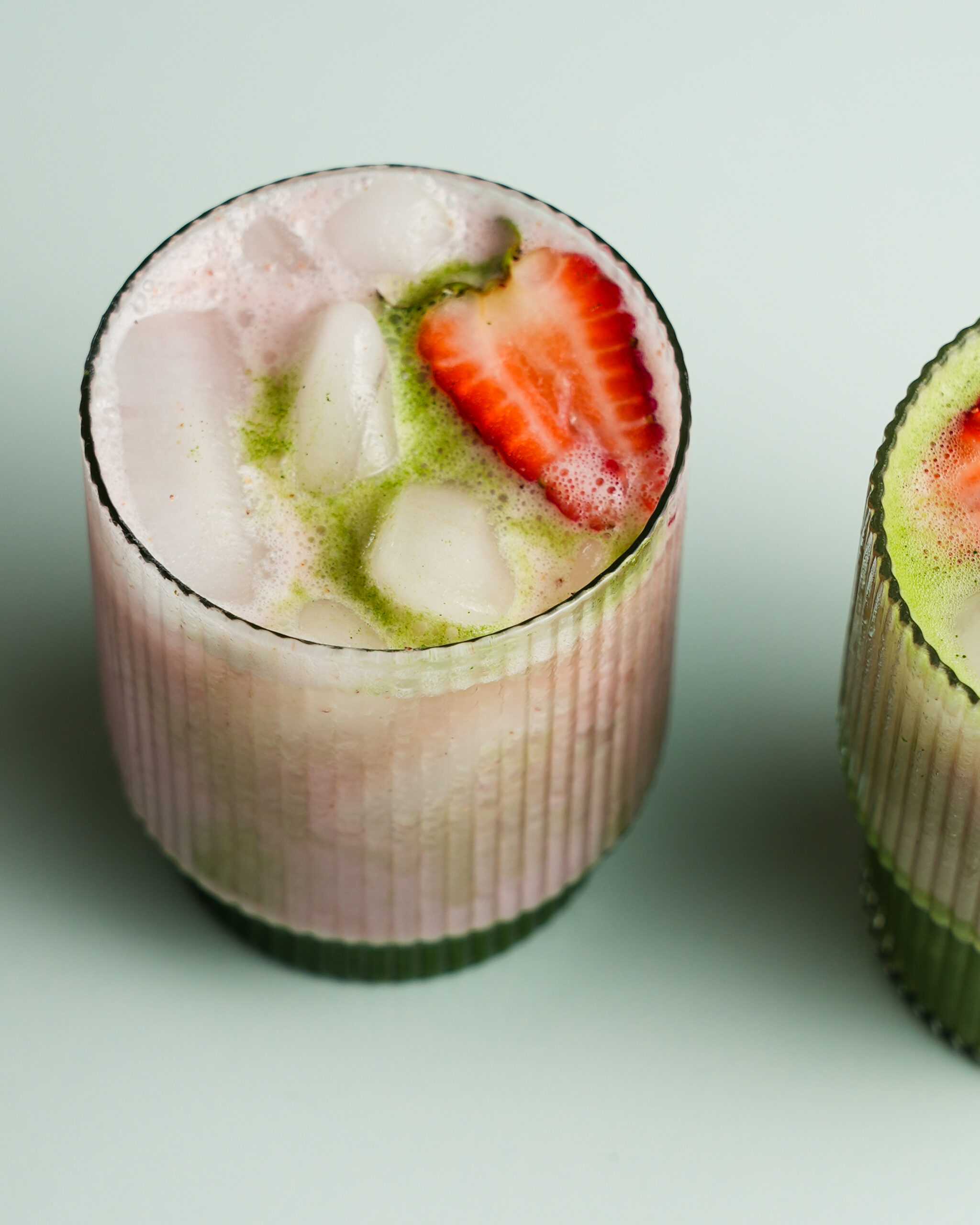 An iced strawberry matcha latte is shown at the forefront of the image, with Califia Farms Almond Barista Blend in the background.