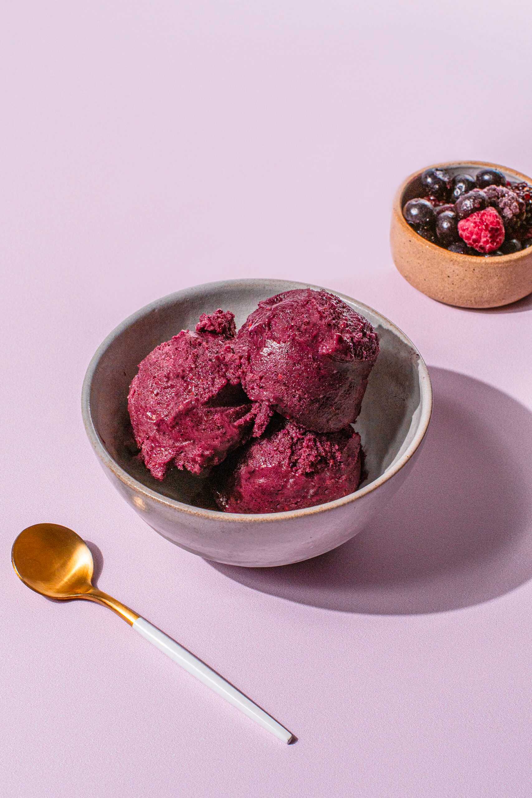 Mixed Berry Ice Cream sits in a bowl at the center of the image to show the finished product of this recipe.