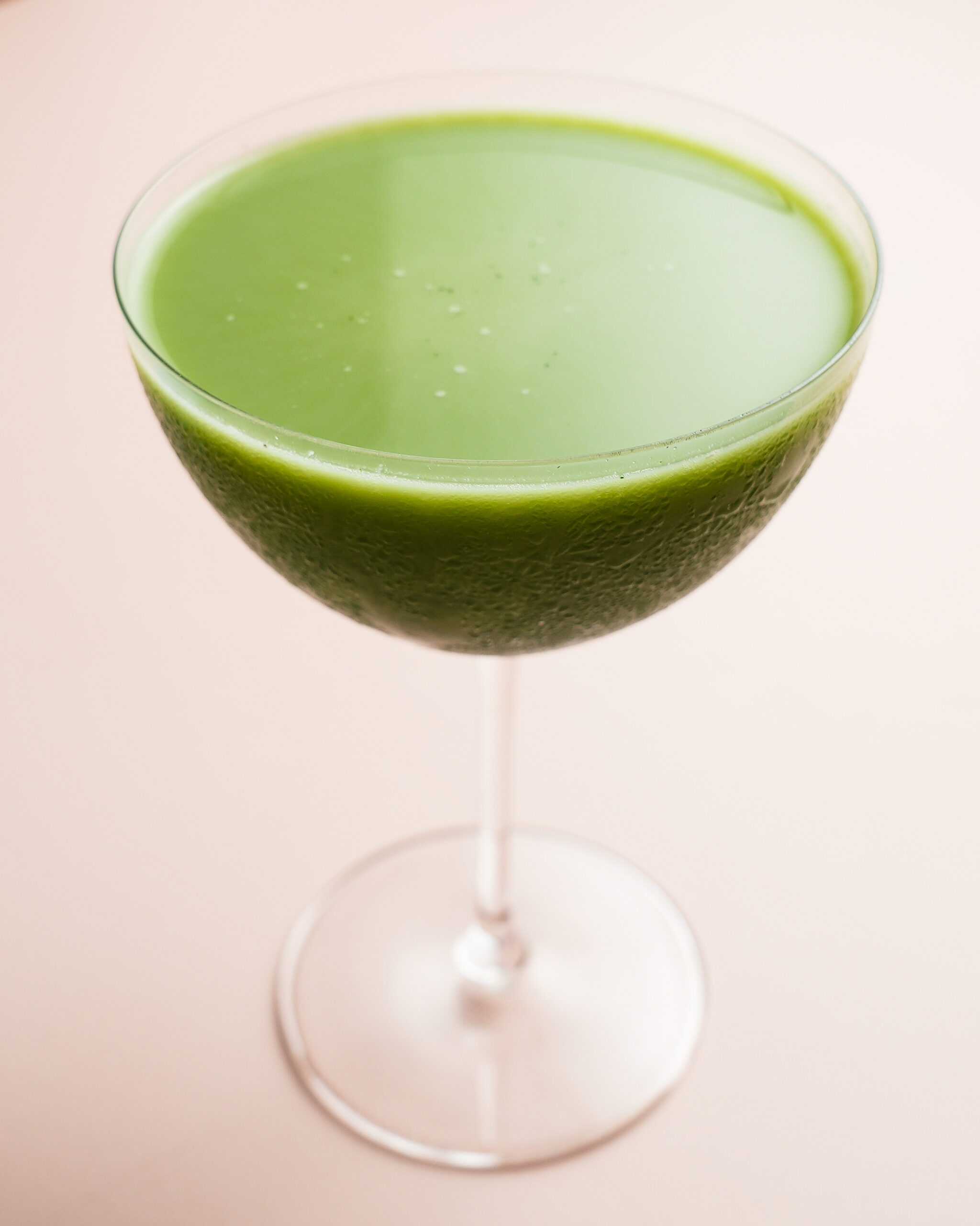 A bright green matcha martini in a stemmed glass sits at the center of the image.